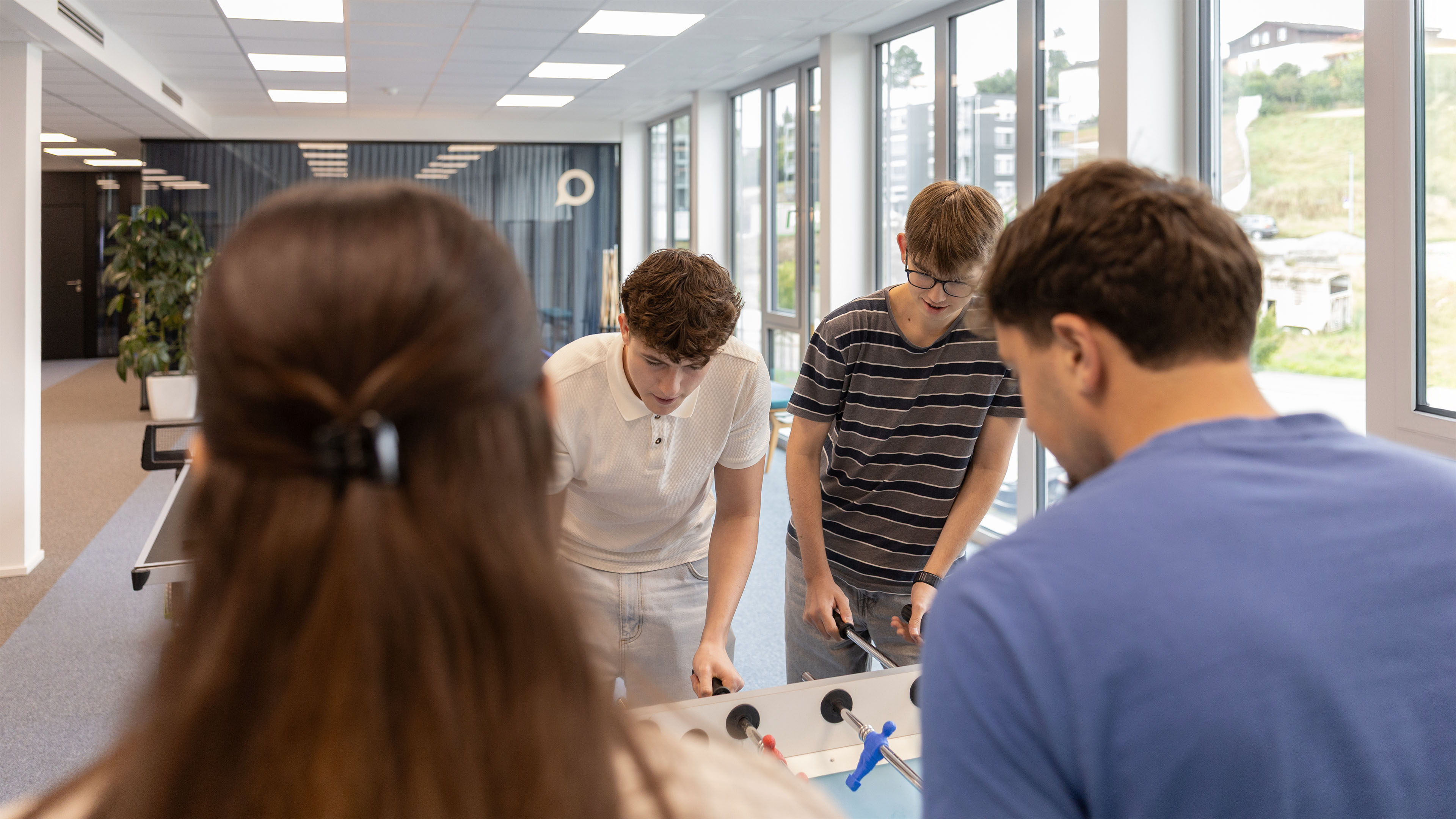 Mehrere Lernende der Voicepoint AG spielen gemeinsam Tischfussball im Büro.