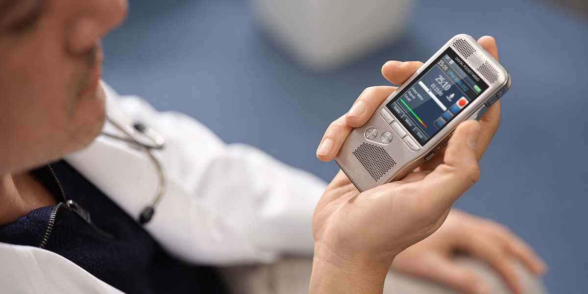 Ein Arzt dikteirt im weissen Kittel mit einem Philips Digital Pocket Memo 8000 Diktiergerät.