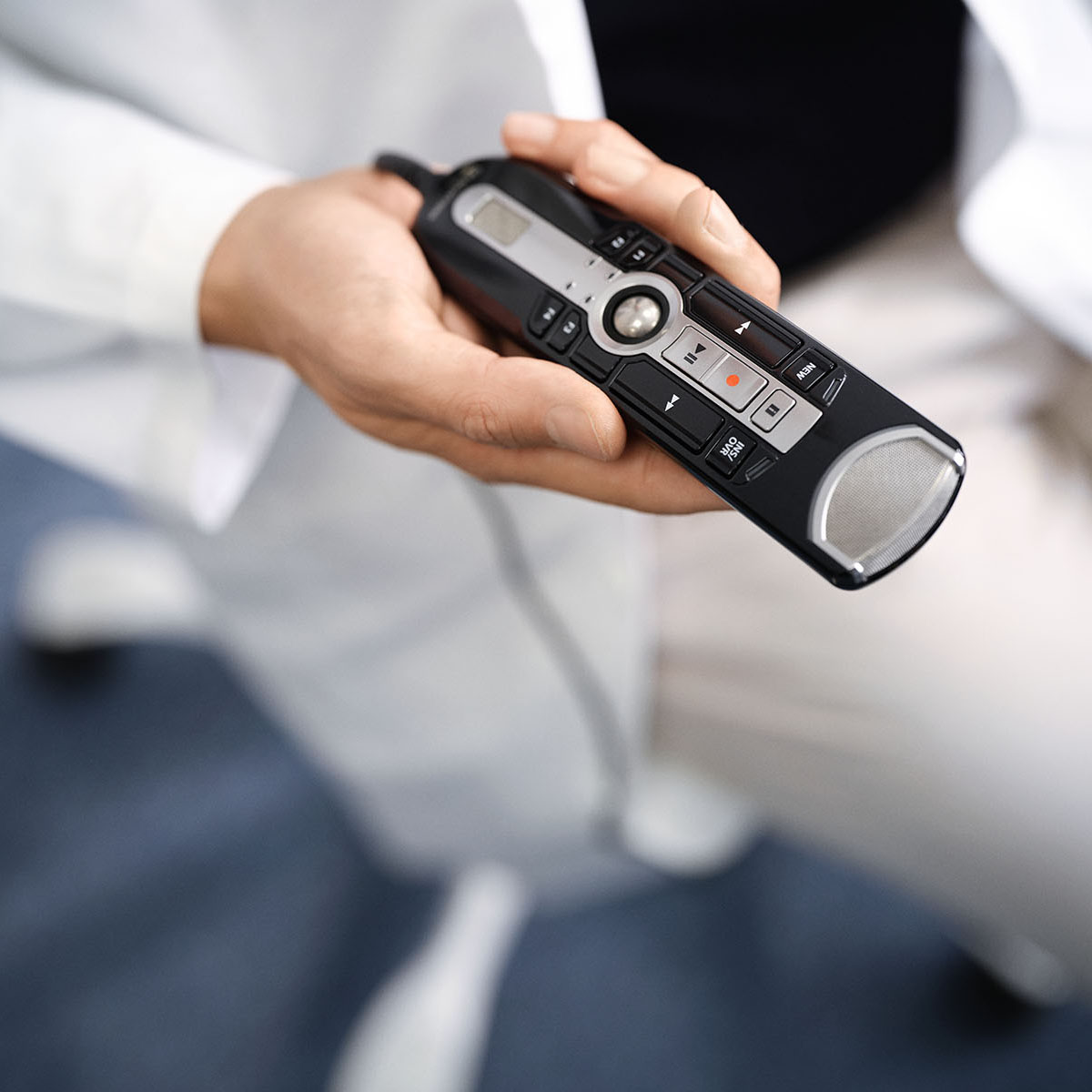 Une main tient un micro de dictée utilisé pour dicter avec Voicepoint Helium.