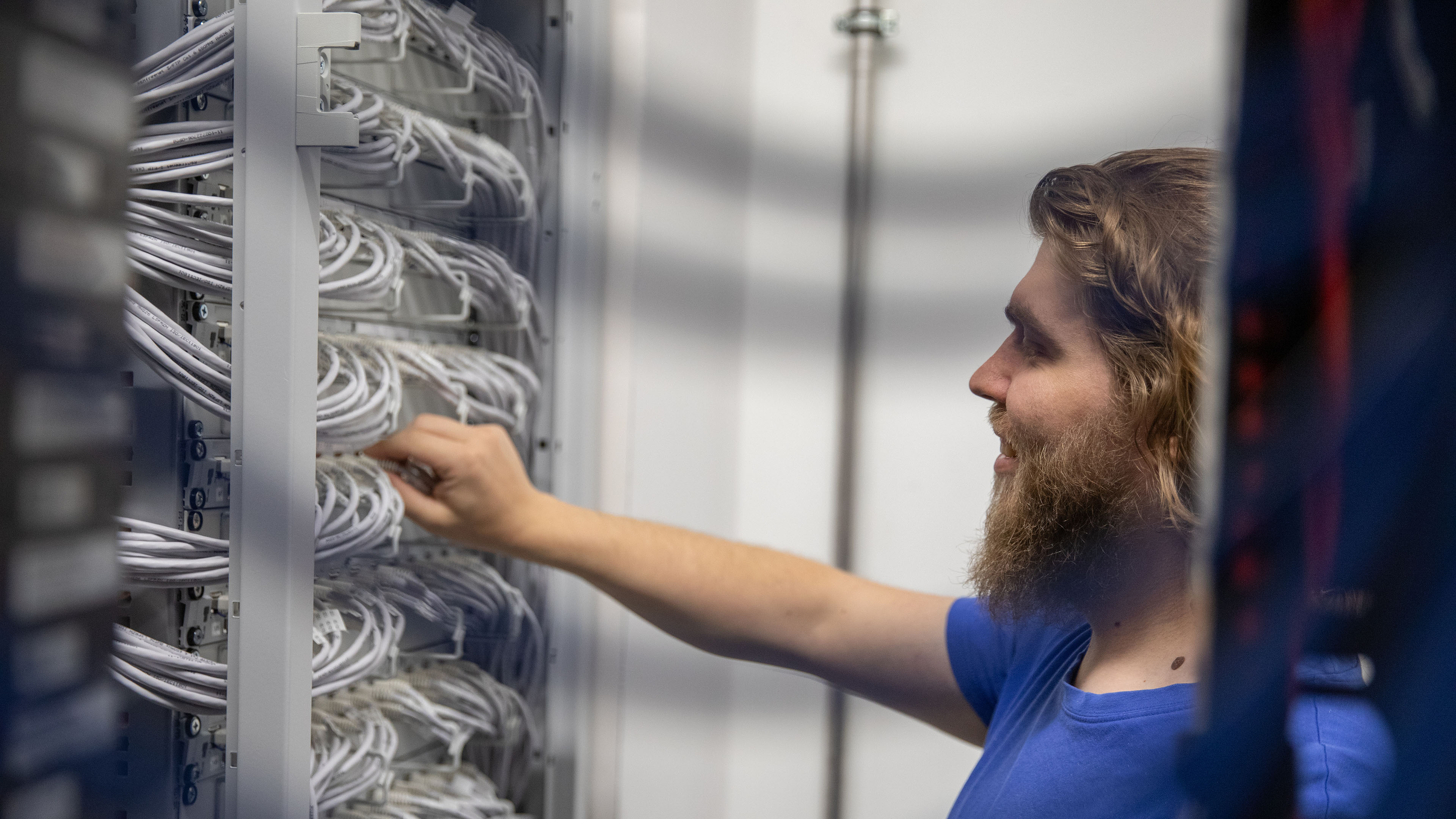 Mitarbeiter der Voicepoint AG kontrolliert Kabelverbindungen am Ethernet-Patchpanel im Technikraum.