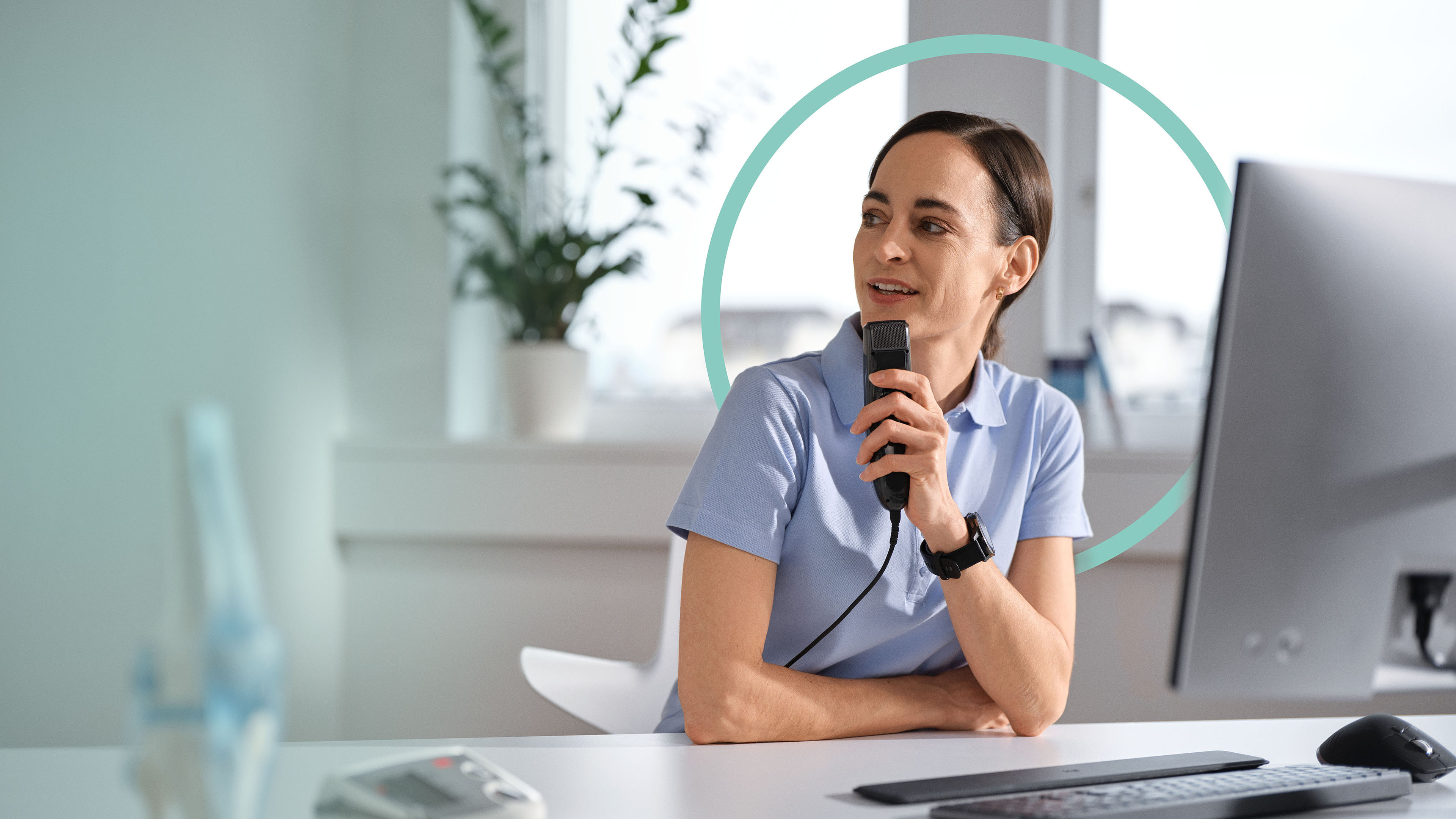 Une femme médecin est assise dans son cabinet, elle dicte à l'aide d'un dictaphone et utilise la reconnaissance vocale médicale. À l'arrière-plan, on aperçoit un cercle bleu servant d'élément décoratif.
