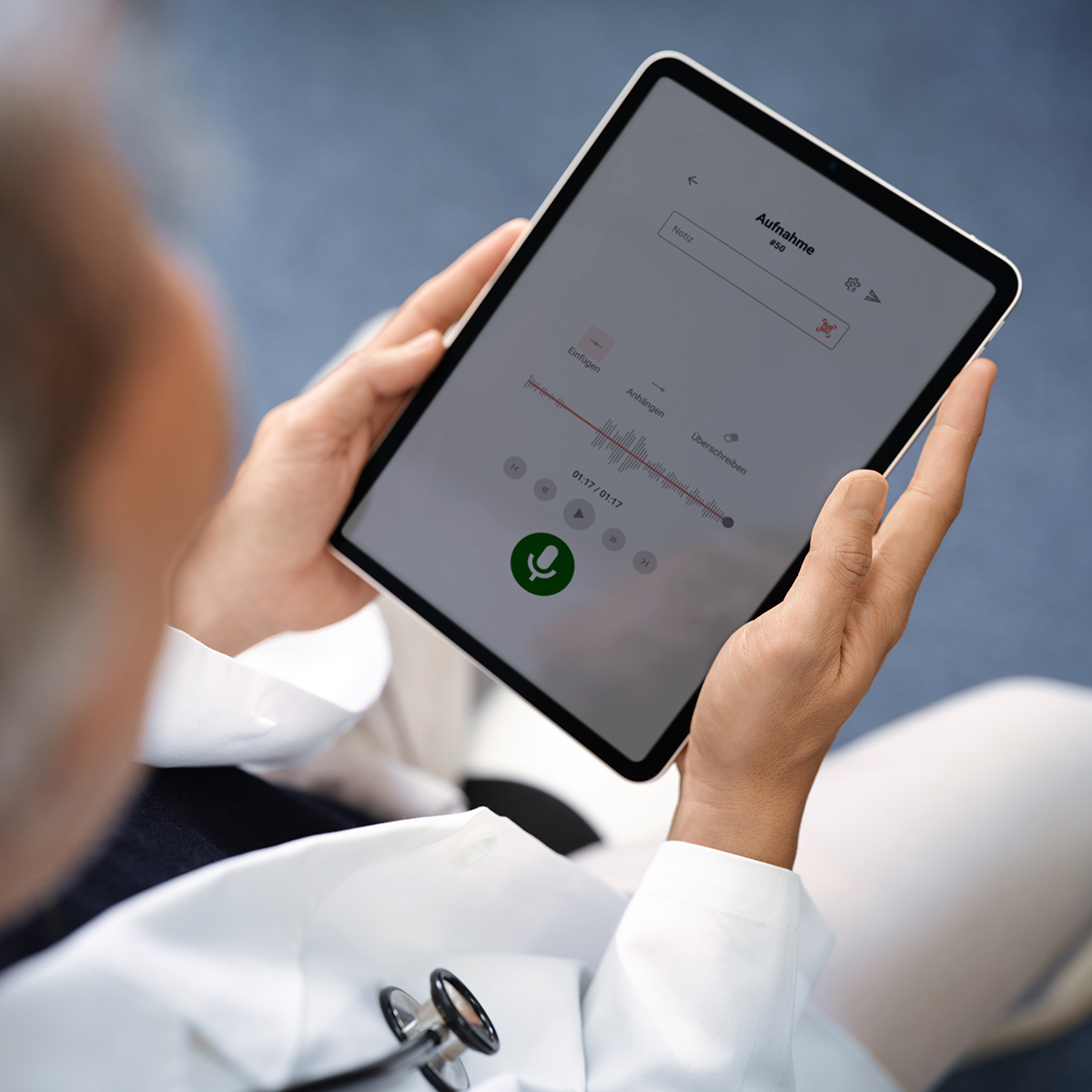 Eine Person im Arztkittel hält ein Tablet in den Händen, auf dem die Benutzeroberfläche von Voicepoint Xenon zu sehen ist.