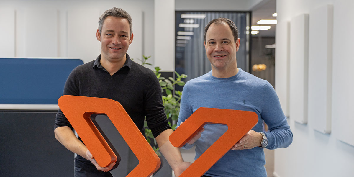 Jonas Blum (links) und Reto Heusser (rechts), Geschäftsleiter und Gründer von Voicepoint, stehen im Voicepoint Büro und halten ein Voicepoint Xenon Logo hoch.