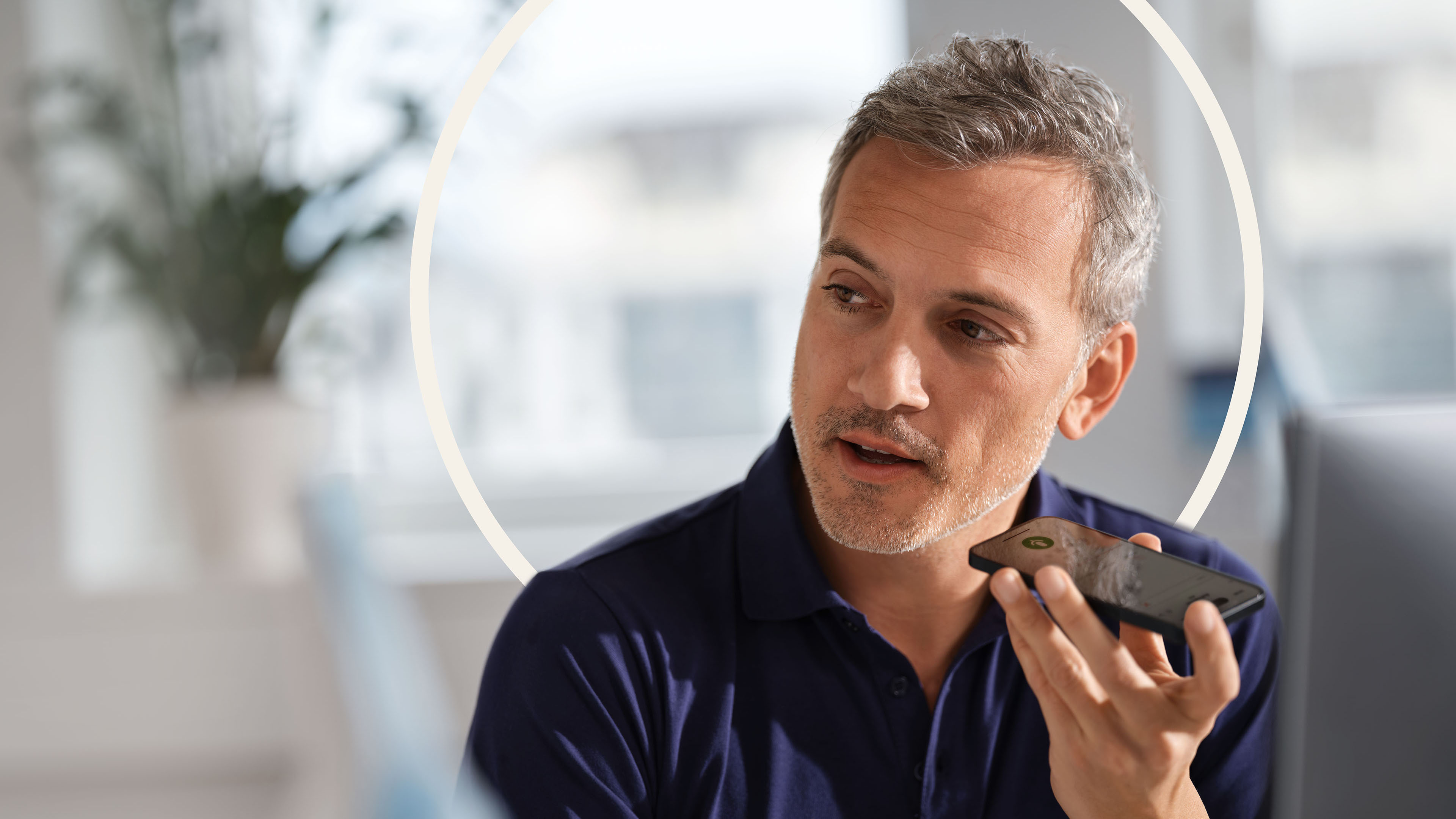 Un médecin en polo bleu dicte à son poste de travail à l'aide d'un smartphone
