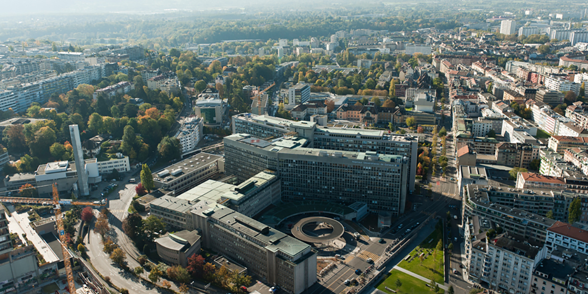 Vue aérienne des Hôpitaux Universitaires de Genève avec le grand complexe hospitalier et la ville environnante.