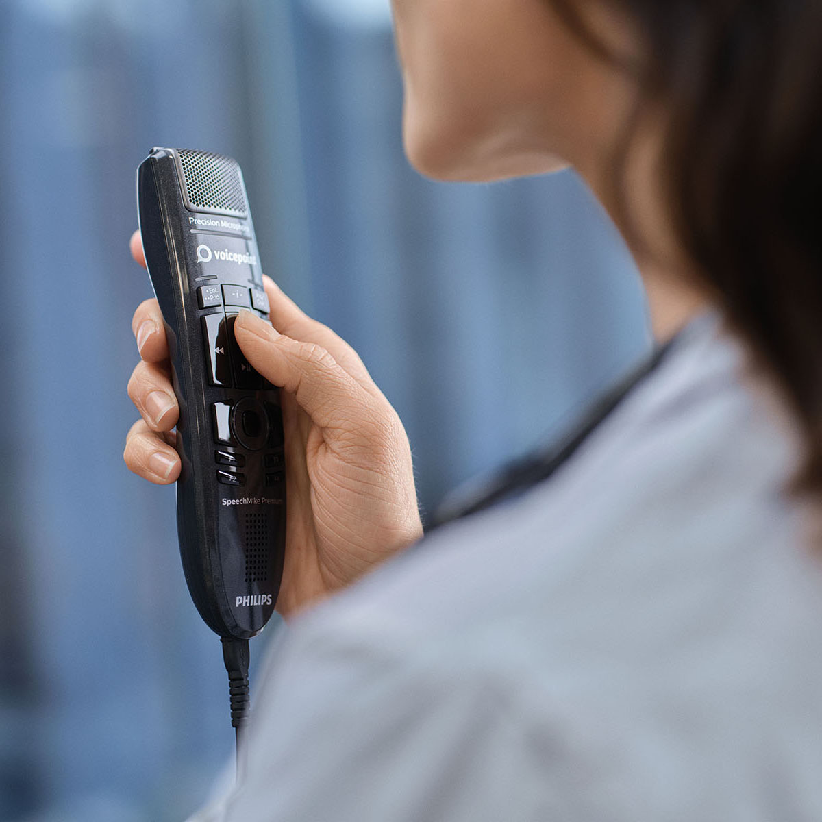 Gros plan sur une médecin utilisant un microphone de dictée et un logiciel de reconnaissance vocale médicale.